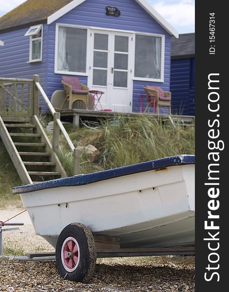 A portrait format image of a blue wooden constructed holiday beach hut with a boat to the foreground. Located at Christchurch, Dorset, England on the South coast. A portrait format image of a blue wooden constructed holiday beach hut with a boat to the foreground. Located at Christchurch, Dorset, England on the South coast.