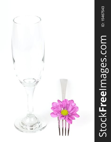 A empty glass and a fork with blossom on a white table. A empty glass and a fork with blossom on a white table