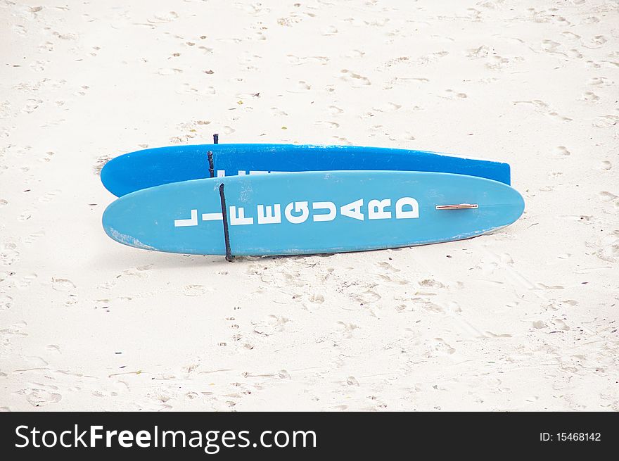 A pair of lifeguard surfboards on a white sand beach