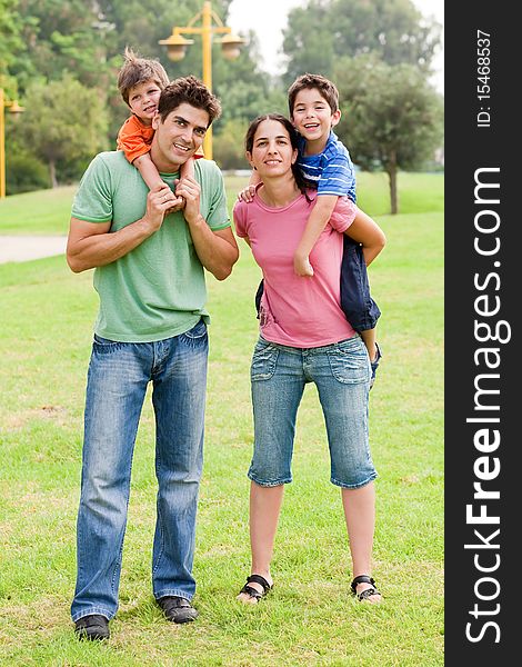 Couple giving piggyback ride to their children and looking into camera