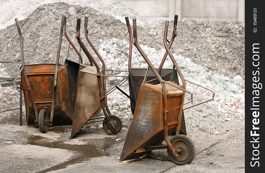 Empty, old wheelbarrows on the background of heaps of rubble, lack of hands to work. Empty, old wheelbarrows on the background of heaps of rubble, lack of hands to work