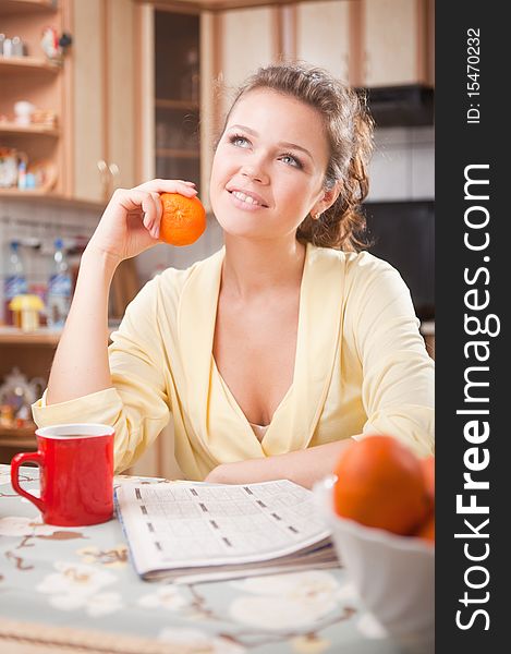 Pretty woman with in the kitchen with fresh orange and cup of tea having a breakfast