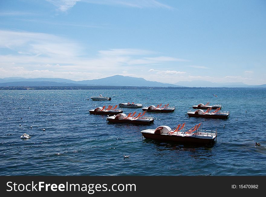 Pedal boats   waiting to be used with lake scene and mountains in the background. Pedal boats   waiting to be used with lake scene and mountains in the background.