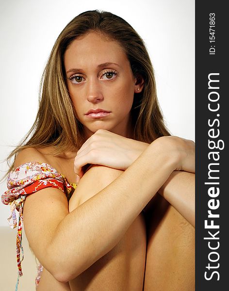 A thoughtful young woman sitting on a sofa with arms on her knees