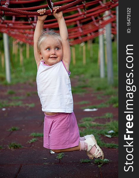 Cute little hanging from red ropes in the park. Cute little hanging from red ropes in the park