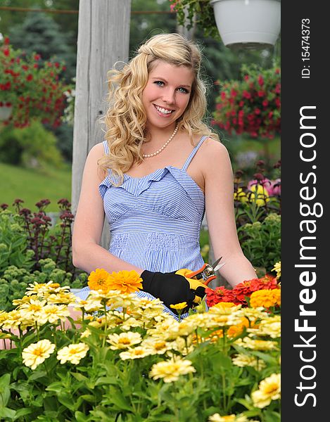 Young beautiful blond girl at the garden surrounded by colorful flowers