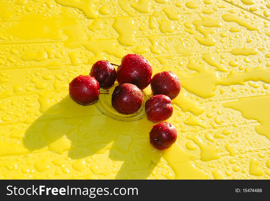 Group of fresh plum on plastic yellow table after rain