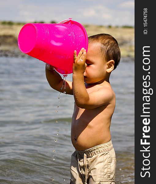 child plays with a bucket on the river. child plays with a bucket on the river