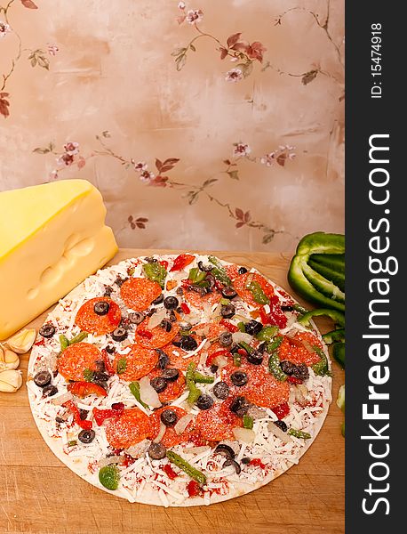 Raw pizza with pepperoni, bell peppers, black olives and onions. Raw pizza with pepperoni, bell peppers, black olives and onions