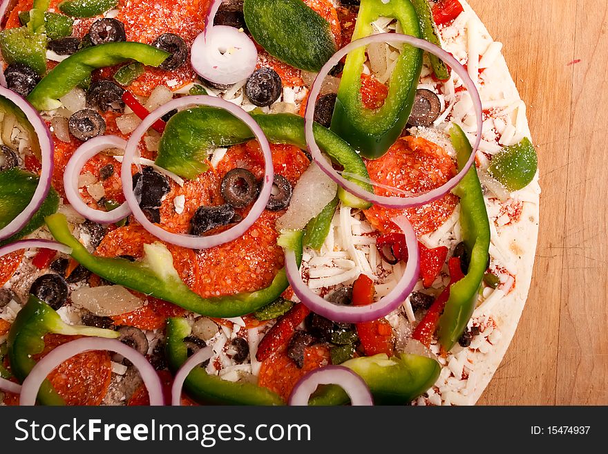 Raw pizza with vegetables and pepperoni