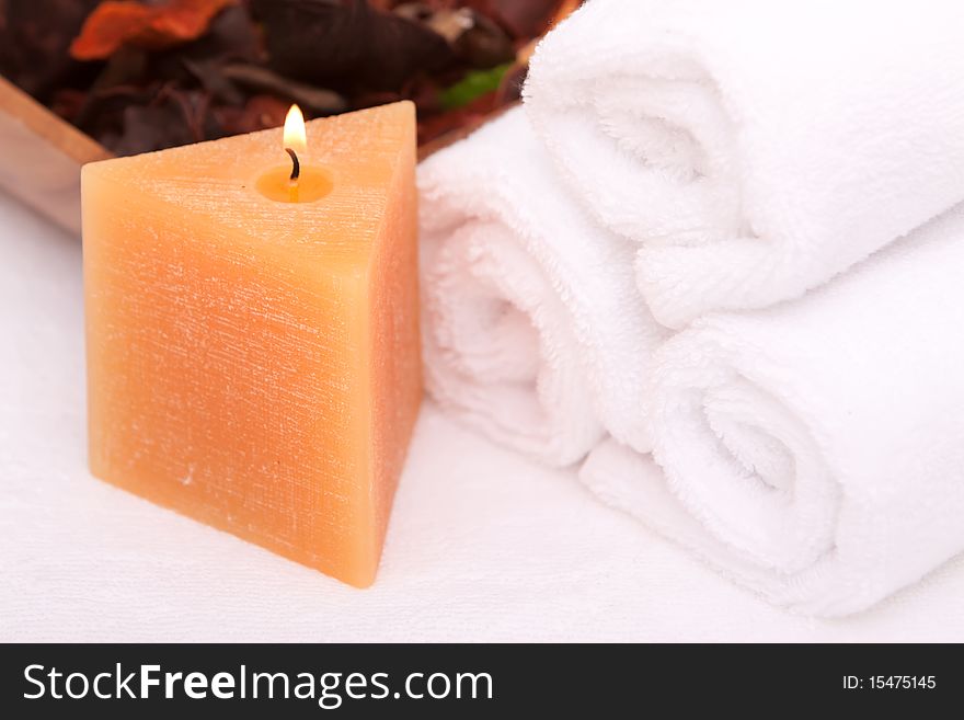 Spa candle with white rolled up towels