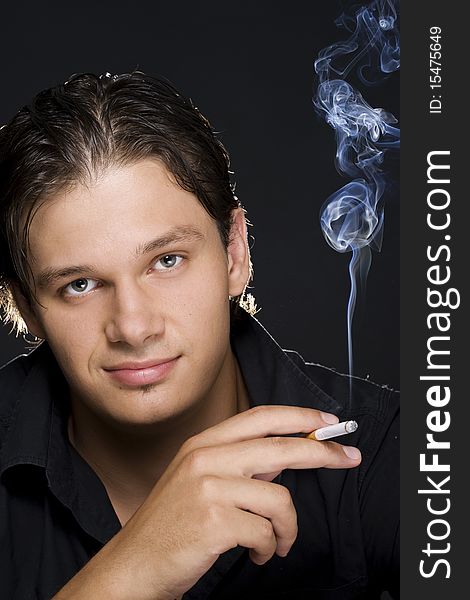 A portrait of a young sexy man smoking a cigarette