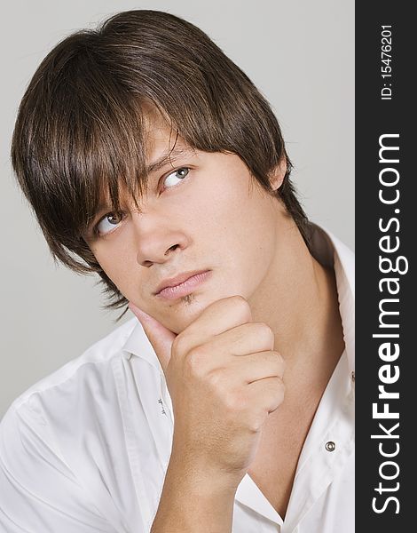 Closeup of a handsome young man thinking against white background