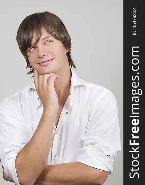 Closeup of a handsome young man thinking against white background