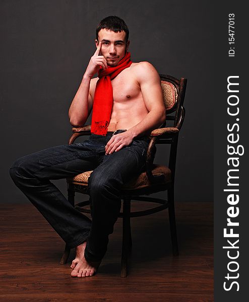 Young fashion man model with athletic body posing with a red scarf. Young fashion man model with athletic body posing with a red scarf