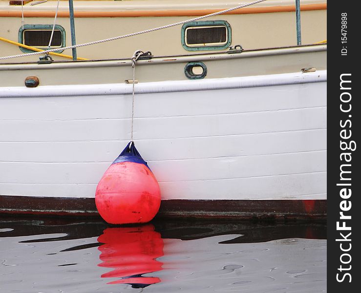 Buoy hanging from the boat into the water, reflecting on the sea. Square format. Buoy hanging from the boat into the water, reflecting on the sea. Square format.