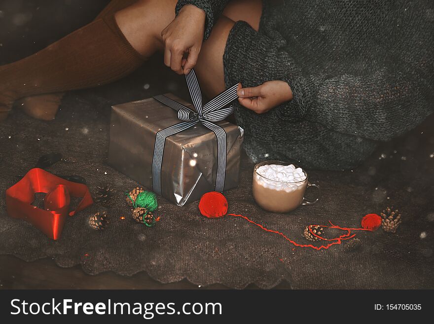 Christmas gift wrap. The woman`s hands packing a Christmas gift box on dark background.