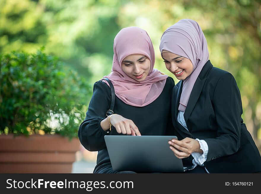 Muslim Female Friends looking at a laptop together. Outdoor shoot.