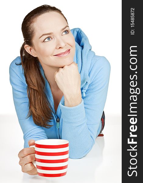 A beautiful young healthy woman lying down with a cup of tea or coffee smiling. A beautiful young healthy woman lying down with a cup of tea or coffee smiling.