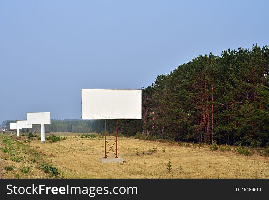 A number of structures along the road, empty, in a forest and sky. A number of structures along the road, empty, in a forest and sky