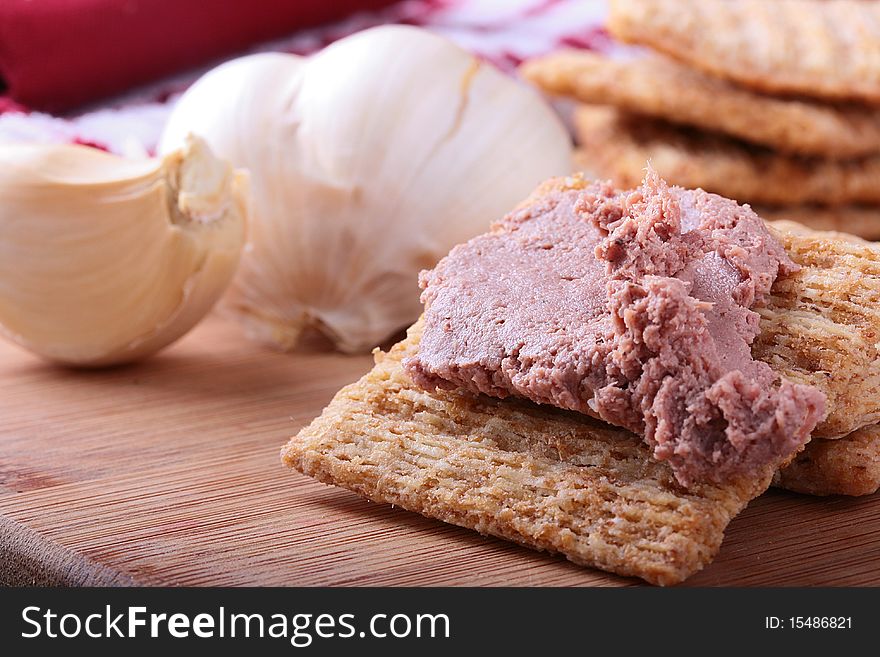 Wheat crackers on a kitchen board with meat paste.