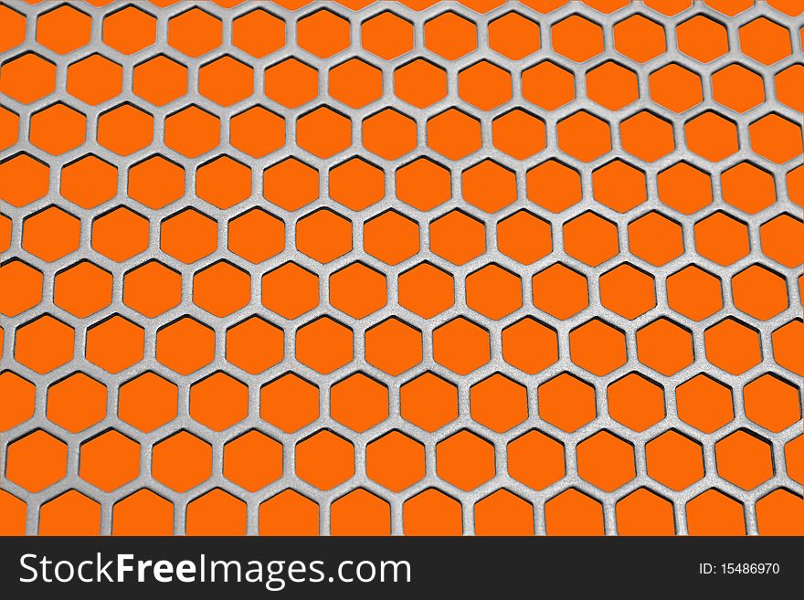 Aluminum honeycomb lattice in the form. Close-up. On an orange background. Aluminum honeycomb lattice in the form. Close-up. On an orange background.