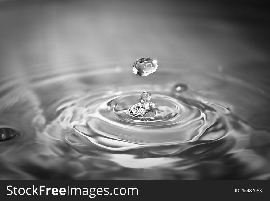 Clean blue drop of water splashing in clear water. Abstract blue background