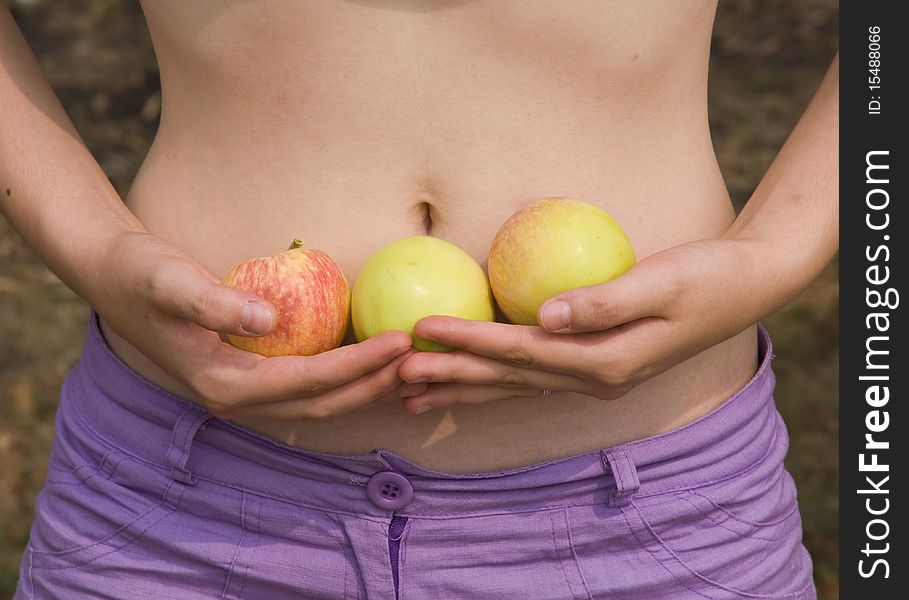Girl holds the apples on a background of the stomach. Girl holds the apples on a background of the stomach