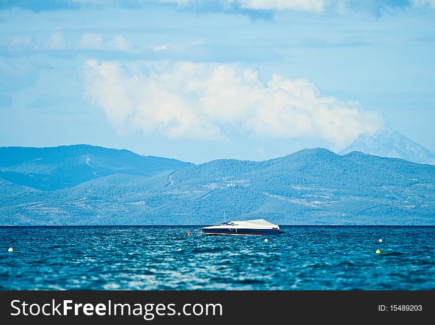 A beautiful white boat against the blue sky, sea and mountains in the background. Greece, Halkidiki, Kassandra. A beautiful white boat against the blue sky, sea and mountains in the background. Greece, Halkidiki, Kassandra.