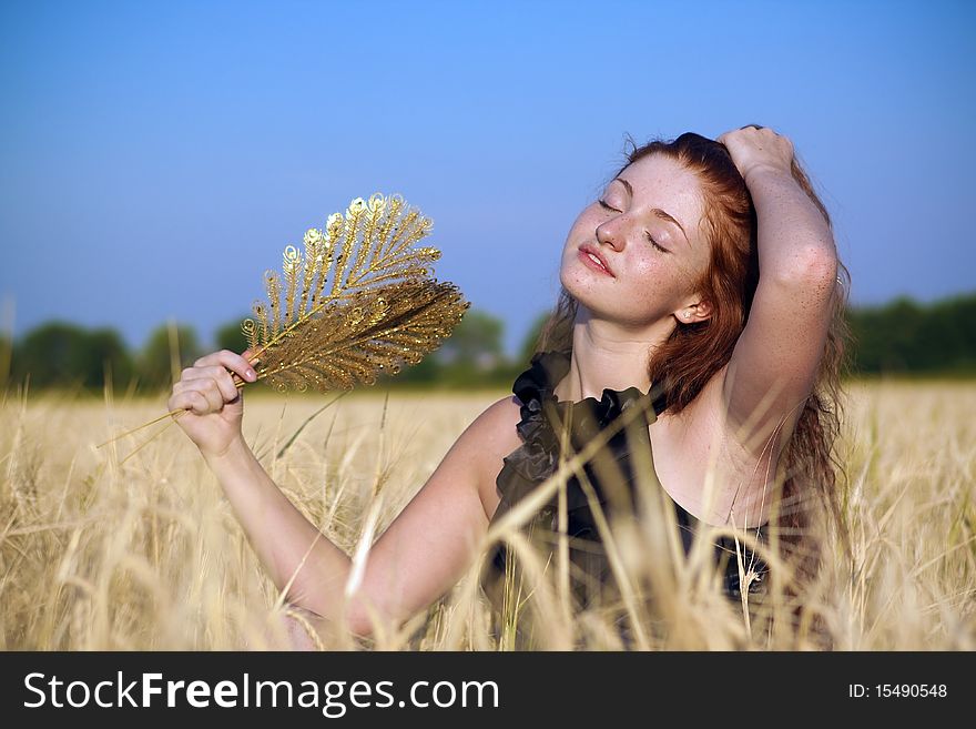 A girl in a field with a golden fan