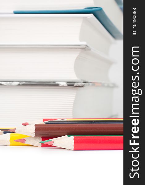 Books and colored pencils on a white background (selective focus)