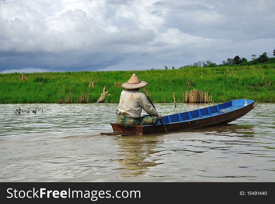 Fisherman and paddle boat in river with cloudy wheather