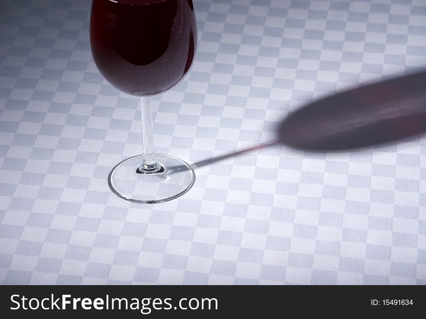 Wine glass and shadow on a checked tablecloth. Wine glass and shadow on a checked tablecloth