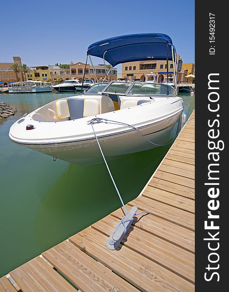 A luxury speedboat moored to a private jetty in a tropical marina. A luxury speedboat moored to a private jetty in a tropical marina