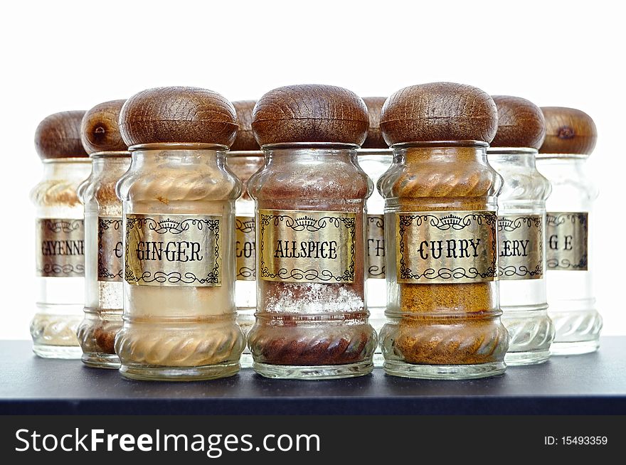 A variety of different spices on a black counter top.