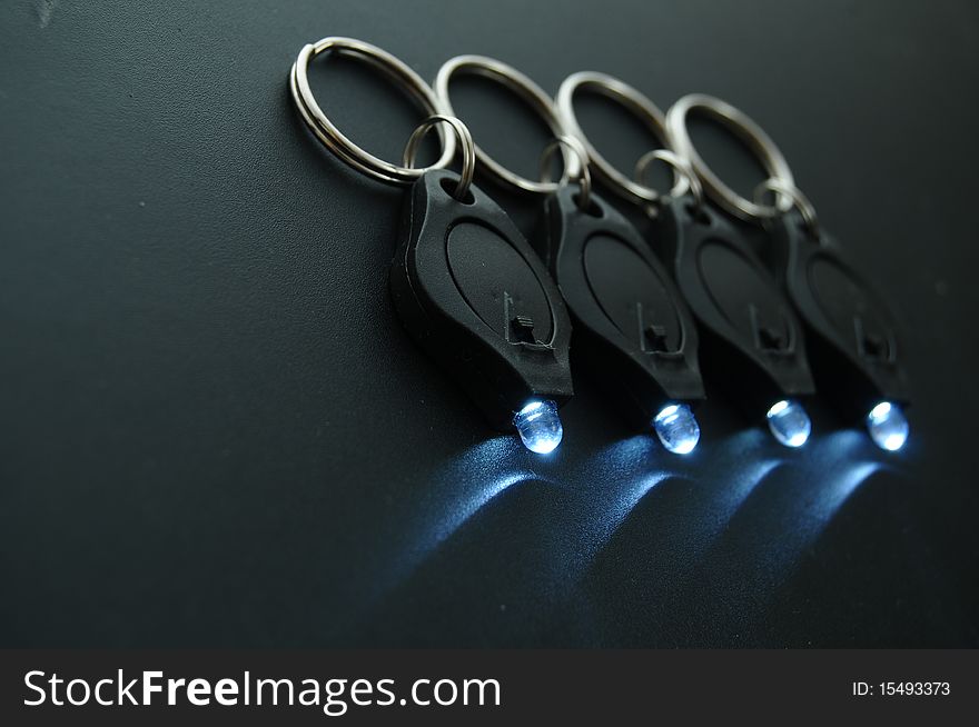 Miniature LED keychain lights on a black surface with shallow depth of field. Miniature LED keychain lights on a black surface with shallow depth of field.