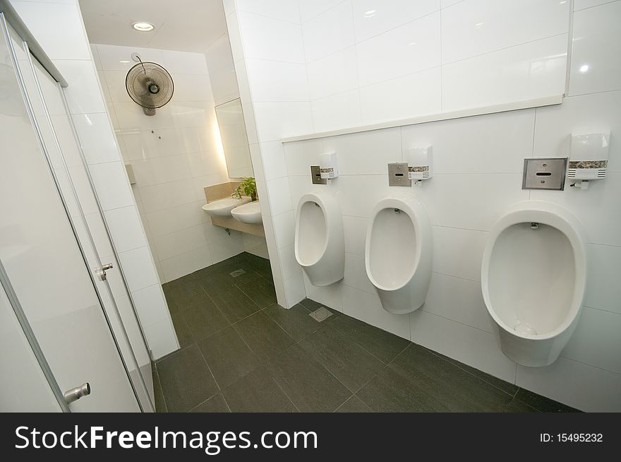 A newly renovated toilet and restroom with sinks, cubicles and urinals. A newly renovated toilet and restroom with sinks, cubicles and urinals.