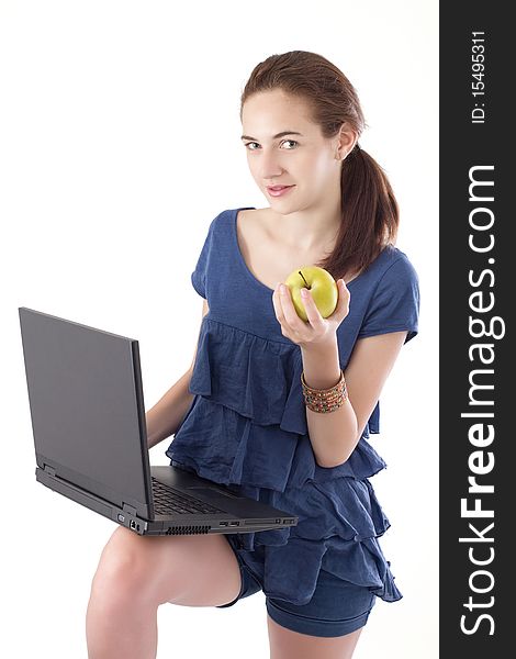 Teen girl, standing, holding laptop and a healthy snack, an apple. Studio shot. Teen girl, standing, holding laptop and a healthy snack, an apple. Studio shot.