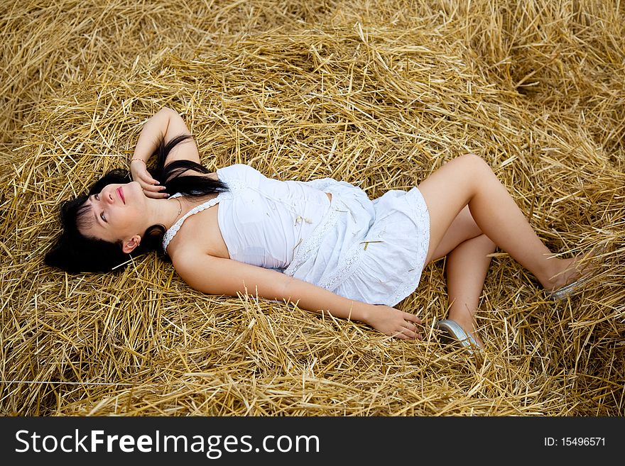 Young beautiful woman is laying on a straw