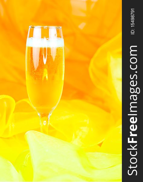 A filled champagne glass on orange and yellow background