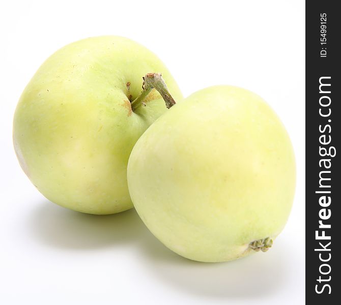 Two green apples with joined by their stems on white background