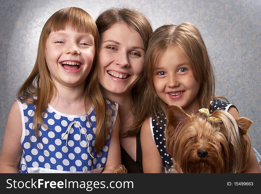 Young mother and two little sisters with Yorkshire terrier over light defocused background. Young mother and two little sisters with Yorkshire terrier over light defocused background