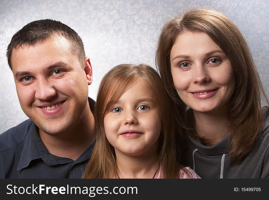 Young mother, father, and daughter over light defocused background. Young mother, father, and daughter over light defocused background
