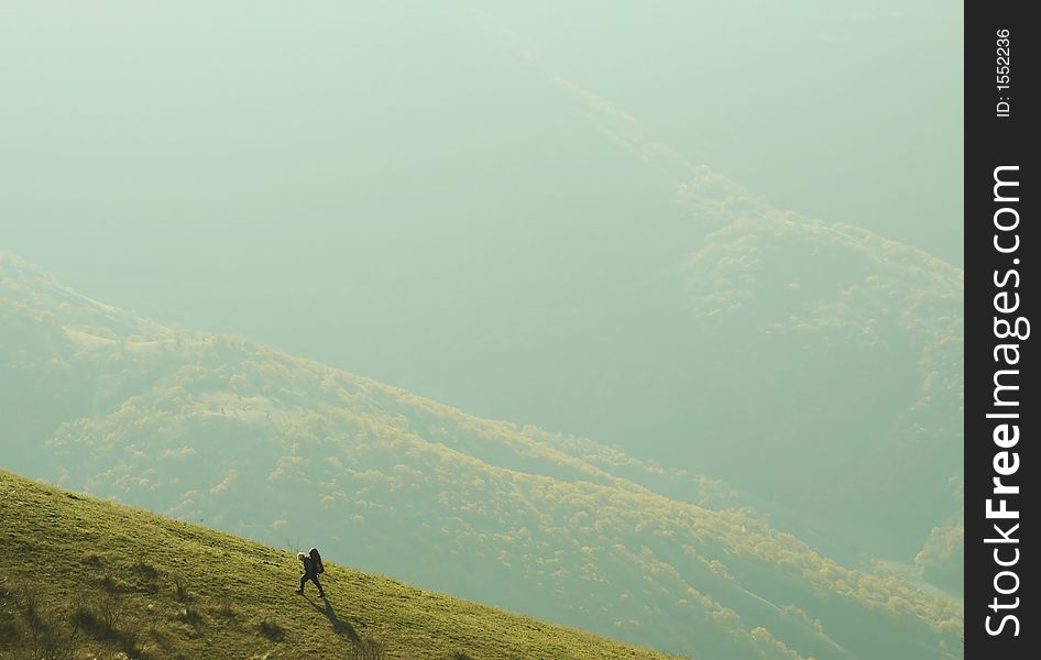 Backpacker going up on the green hill. Backpacker going up on the green hill