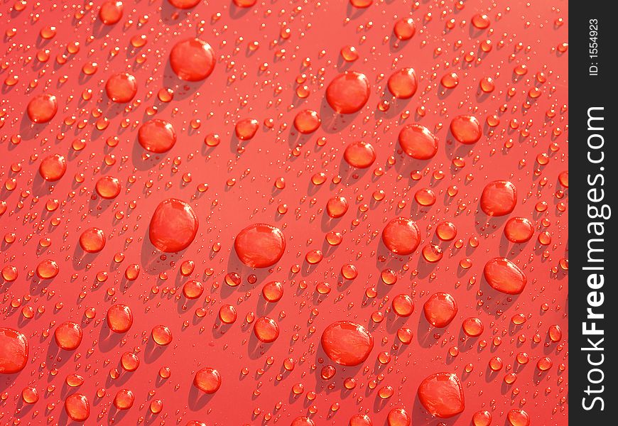 Rain droplets formed on red metallic surface