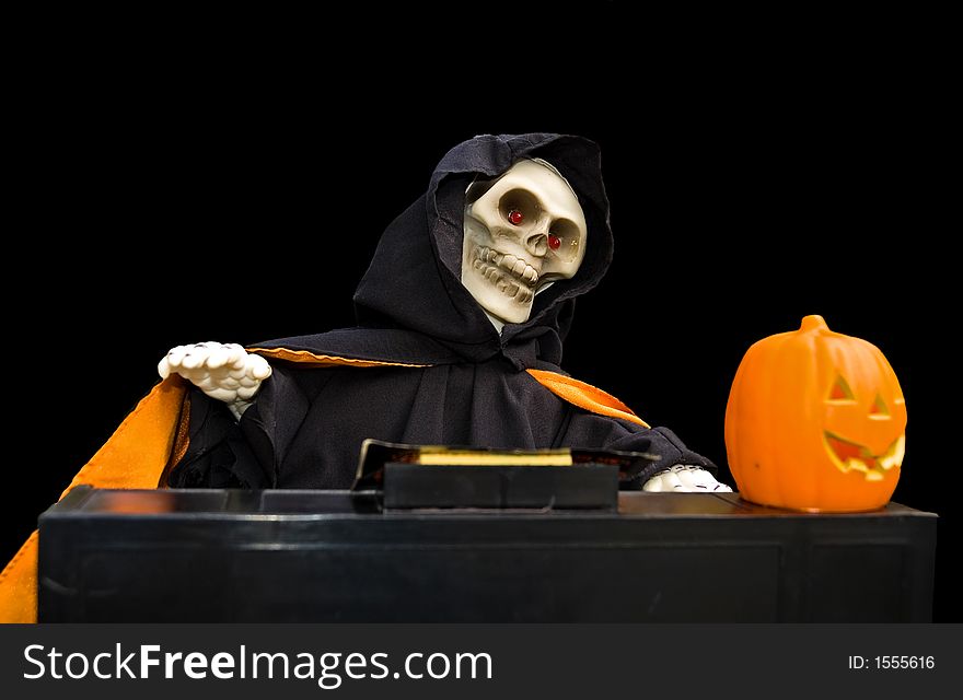 Halloween doll of a ghoul playing a piano with a carved pumpkin on it isolated on a black background. Halloween doll of a ghoul playing a piano with a carved pumpkin on it isolated on a black background