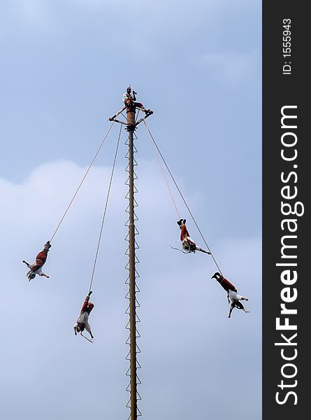 Mexican acrobats performing on spiraling pole.