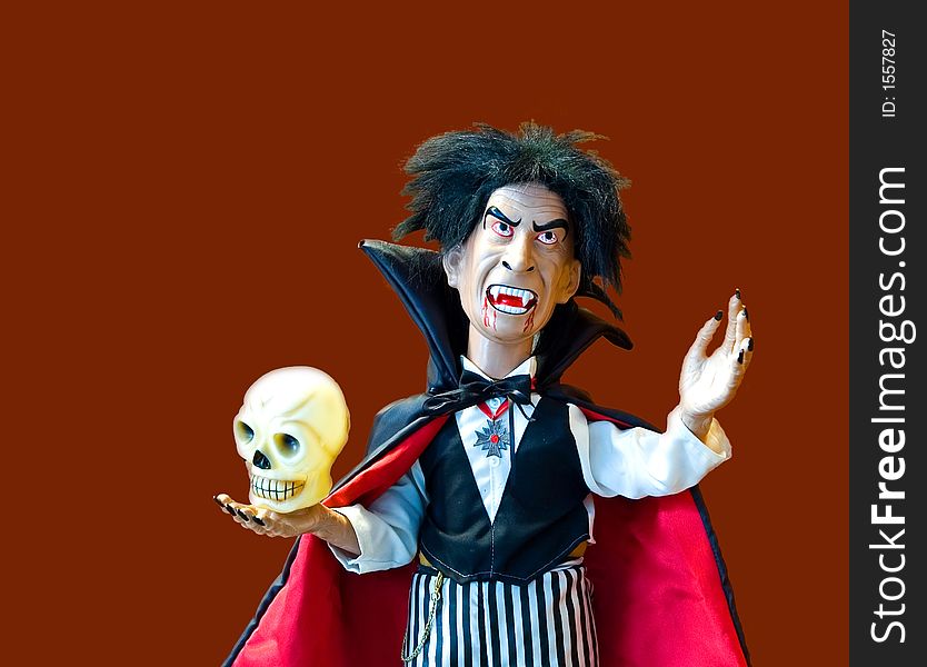 Halloween doll dressed up as of a vampire holding a skull - isolated. Halloween doll dressed up as of a vampire holding a skull - isolated