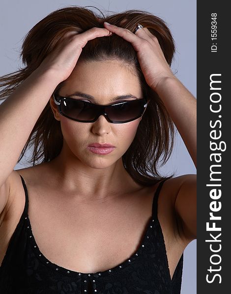 Sexy brunette model with sunglasses and black dress