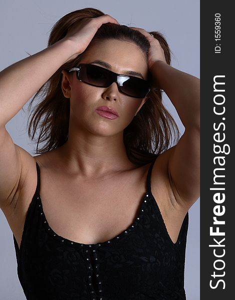Sexy brunette model with sunglasses and black dress